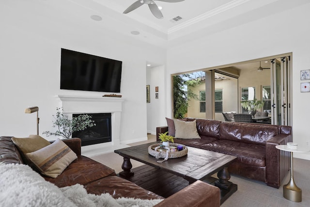 living room featuring crown molding, a tray ceiling, a high ceiling, and ceiling fan