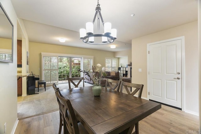 dining space with light hardwood / wood-style floors and an inviting chandelier