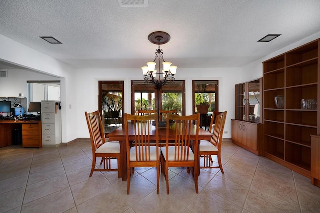 dining room with a notable chandelier, light tile patterned floors, and a textured ceiling