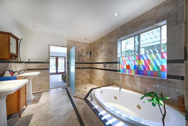 bathroom with french doors, sink, plus walk in shower, and tile walls