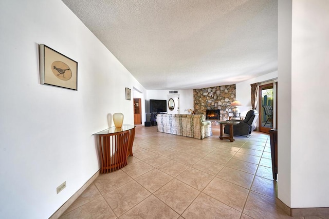 tiled living room with a stone fireplace and a textured ceiling