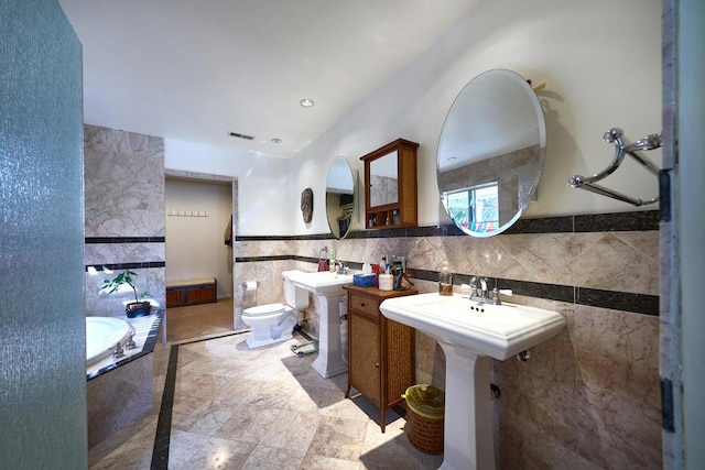 bathroom featuring a bath, toilet, and tile walls