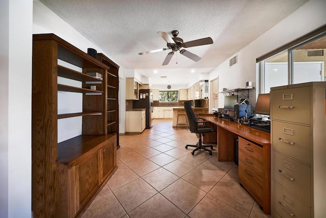 tiled home office with ceiling fan and a textured ceiling