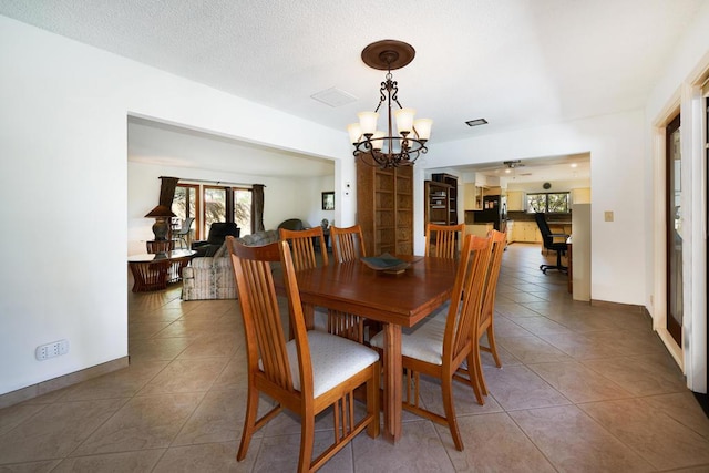 dining room with tile patterned floors, ceiling fan with notable chandelier, and a textured ceiling