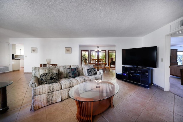 living room featuring tile patterned floors, a textured ceiling, and an inviting chandelier