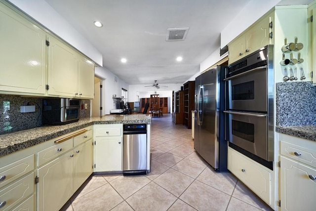 kitchen with kitchen peninsula, appliances with stainless steel finishes, tasteful backsplash, ceiling fan, and light tile patterned flooring