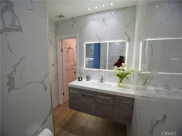 full bath featuring visible vents, vanity, and wood finished floors