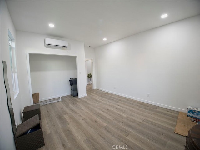 unfurnished living room with light wood-type flooring, an AC wall unit, and recessed lighting