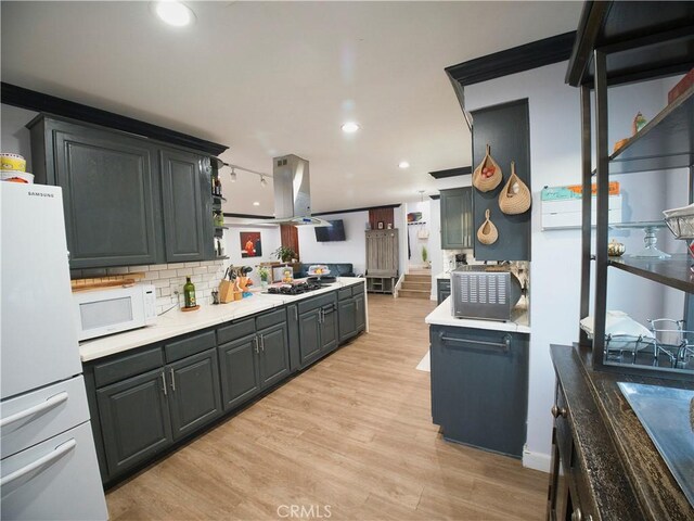 kitchen with island exhaust hood, light countertops, decorative backsplash, light wood-style floors, and white appliances