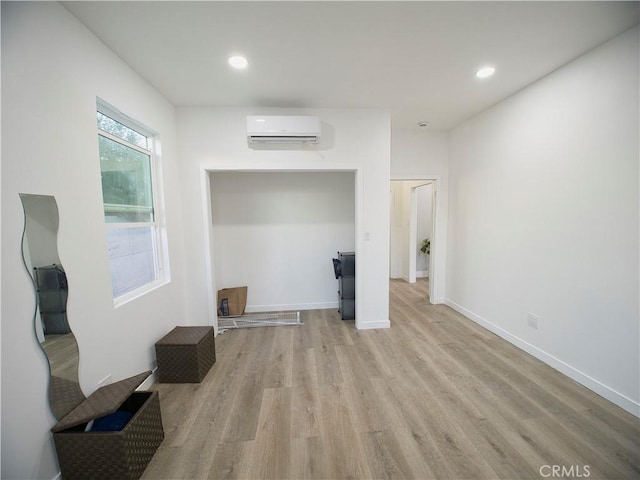 interior space featuring baseboards, a wall mounted AC, light wood-type flooring, and recessed lighting