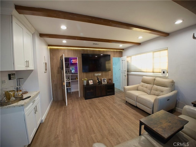 living area with light wood-type flooring, baseboards, beam ceiling, and recessed lighting