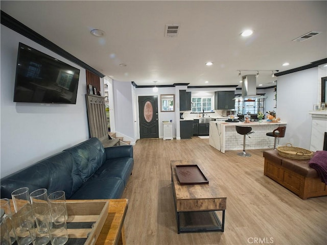 living room with crown molding, light wood-style flooring, visible vents, and recessed lighting