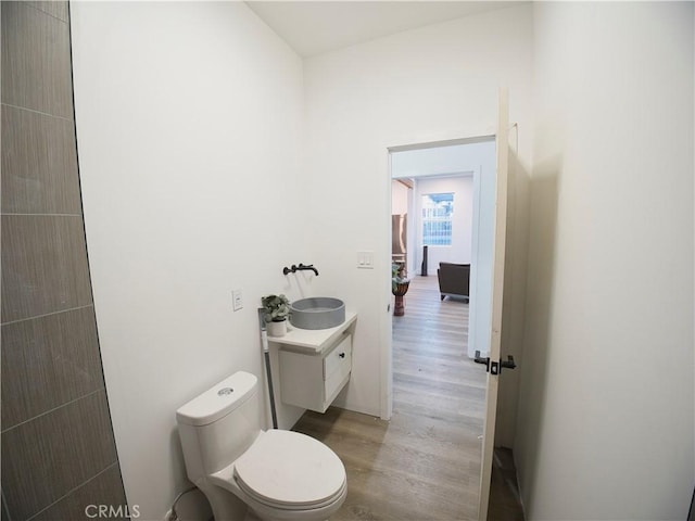 half bath featuring toilet, wood finished floors, and vanity