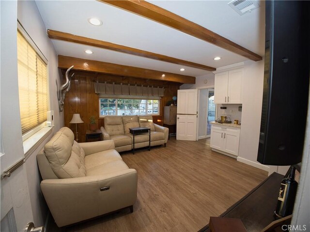 living area with recessed lighting, visible vents, wood finished floors, beamed ceiling, and baseboards