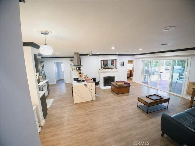 living room with light wood-style flooring, a fireplace, ornamental molding, and recessed lighting