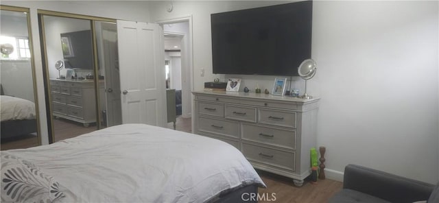 bedroom with a closet, dark wood finished floors, and baseboards