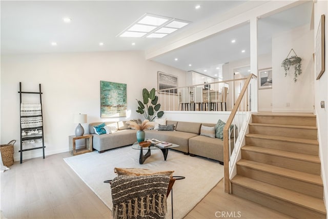 living room featuring vaulted ceiling with beams and light hardwood / wood-style floors