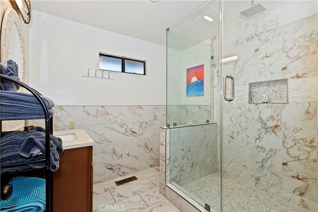 bathroom with tile walls, vanity, and a shower with door