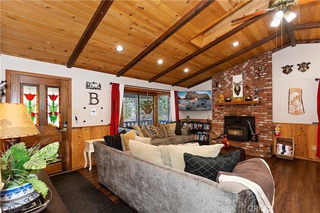 living room featuring dark wood-type flooring, vaulted ceiling with beams, wooden ceiling, a wood stove, and wooden walls