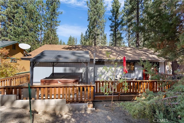 rear view of property featuring a hot tub and a wooden deck