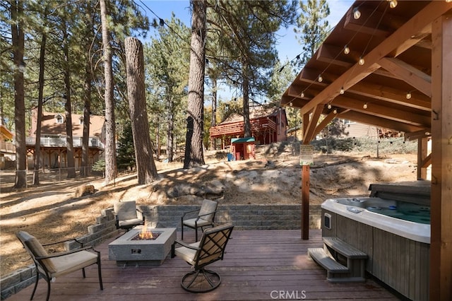 wooden deck with a hot tub and an outdoor fire pit