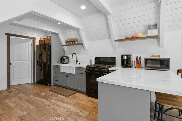 kitchen featuring sink, black gas range, light hardwood / wood-style floors, gray cabinets, and refrigerator with ice dispenser