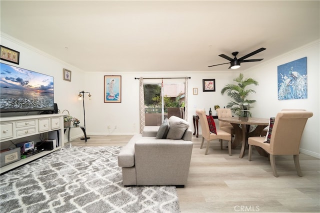 living room featuring ceiling fan, ornamental molding, and light wood-type flooring