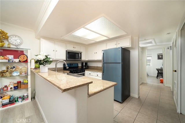 kitchen featuring sink, kitchen peninsula, stainless steel appliances, white cabinets, and ornamental molding