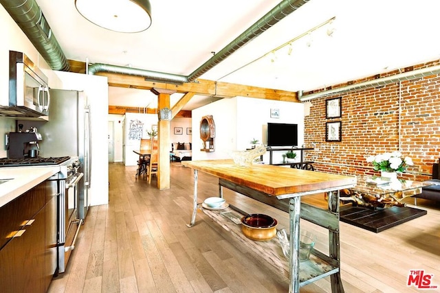 kitchen featuring appliances with stainless steel finishes, light hardwood / wood-style flooring, dark brown cabinets, and brick wall