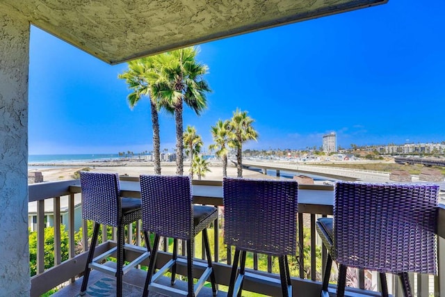 balcony with a water view and a view of the beach