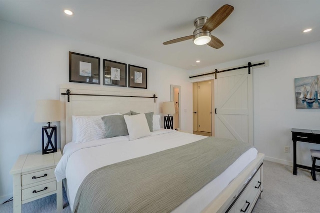 bedroom featuring ceiling fan, a barn door, and light colored carpet