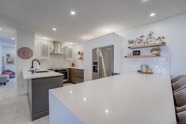 kitchen featuring a breakfast bar area, stainless steel appliances, wall chimney exhaust hood, and kitchen peninsula