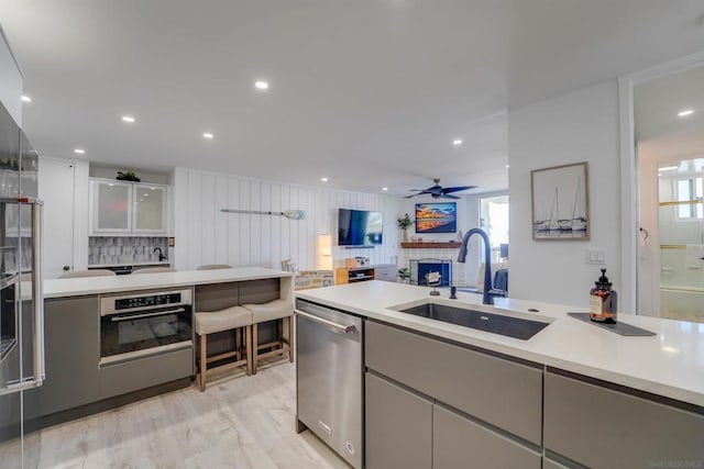 kitchen featuring light wood-type flooring, ceiling fan, stainless steel appliances, and sink