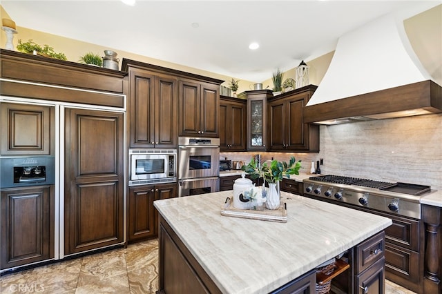 kitchen featuring dark brown cabinetry, custom range hood, tasteful backsplash, and built in appliances