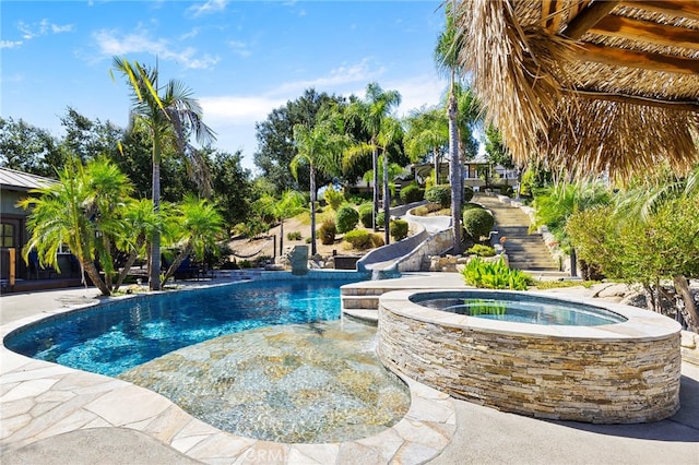 view of swimming pool featuring a water slide and an in ground hot tub