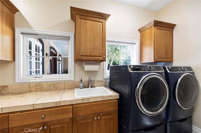 washroom featuring sink, washing machine and clothes dryer, and cabinets