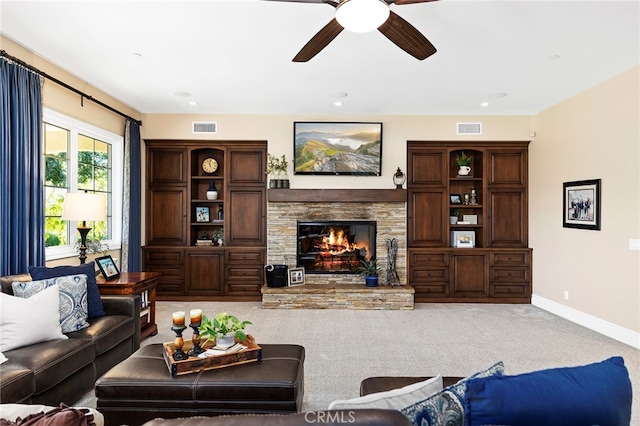 living room with carpet, a stone fireplace, and ceiling fan