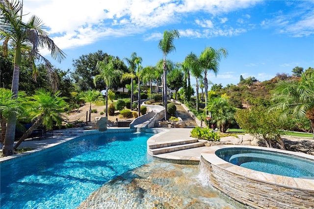 view of pool featuring a water slide and an in ground hot tub