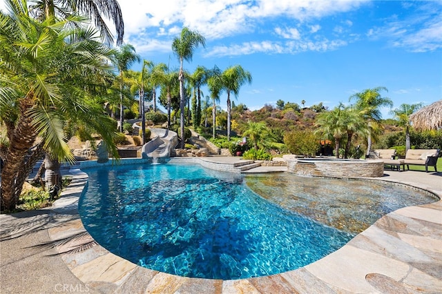 view of pool featuring a water slide, a patio, and an in ground hot tub