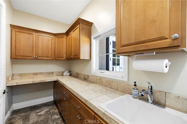14179 Woods Valley Rd, Valley Center, CA 92082 - kitchen featuring stone finish flooring, brown cabinetry, a sink, and built in study area