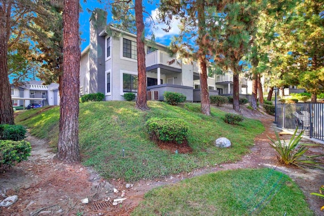 view of front of home with a balcony, a front lawn, and central AC unit