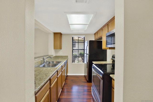 kitchen with light stone countertops, a skylight, sink, stainless steel appliances, and dark hardwood / wood-style floors