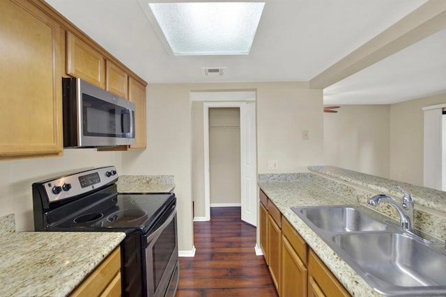 kitchen featuring dark hardwood / wood-style floors, sink, light stone countertops, appliances with stainless steel finishes, and a skylight