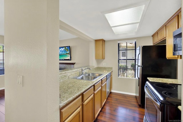 kitchen featuring dark hardwood / wood-style floors, stainless steel appliances, sink, light stone countertops, and a skylight