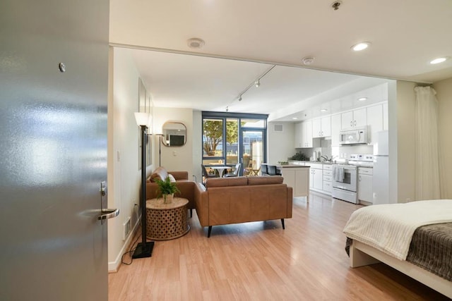 bedroom with light hardwood / wood-style floors and white fridge