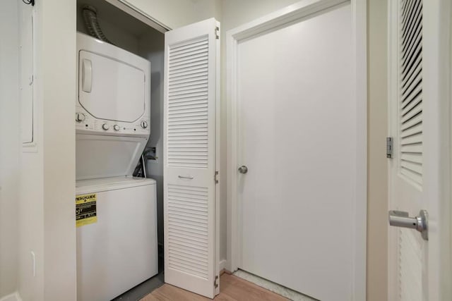 clothes washing area with light wood-type flooring and stacked washer and clothes dryer