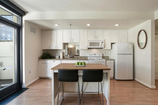 kitchen featuring white cabinetry, a kitchen island, and white appliances