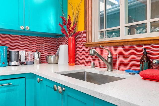 interior details with blue cabinets, sink, and light stone counters