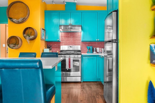 kitchen featuring dark wood-type flooring, backsplash, appliances with stainless steel finishes, and blue cabinets