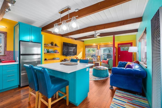 kitchen featuring stainless steel fridge, a breakfast bar area, dark hardwood / wood-style floors, pendant lighting, and a center island